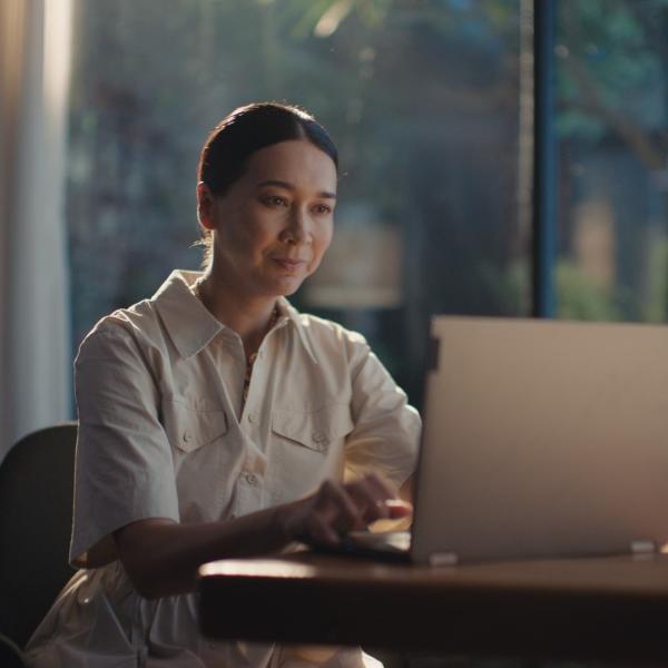 person with a slight smile looking at a laptop